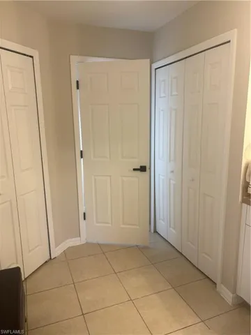 Hall featuring light tile patterned floors and baseboards