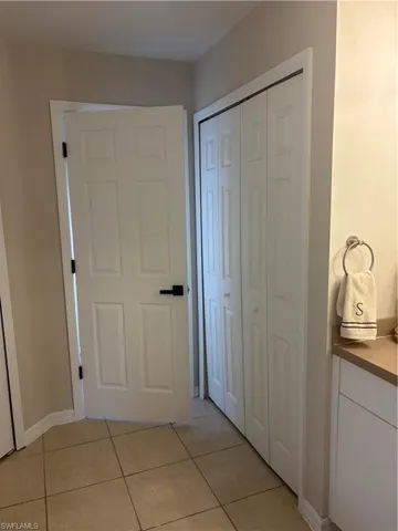 Hall with light tile patterned flooring and baseboards