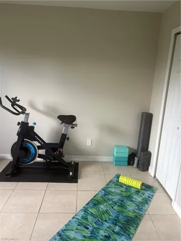 Exercise area with tile patterned flooring and baseboards
