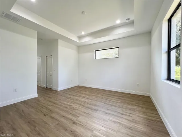 Unfurnished room featuring a tray ceiling and light wood-type flooring