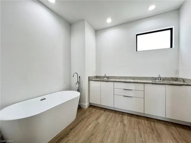 Bathroom with hardwood / wood-style floors, vanity, and a bath