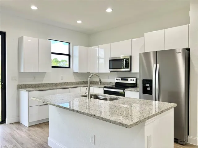 Kitchen with appliances with stainless steel finishes, sink, and white cabinetry
