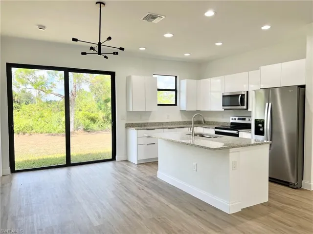 Kitchen featuring an island with sink, appliances with stainless steel finishes, sink, and white cabinetry