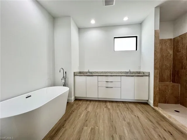 Bathroom featuring plus walk in shower, hardwood / wood-style floors, and vanity