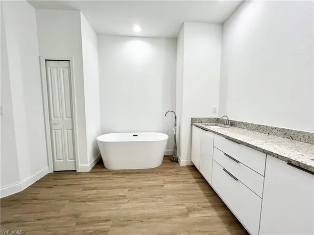 Bathroom with hardwood / wood-style floors, a tub to relax in, and vanity