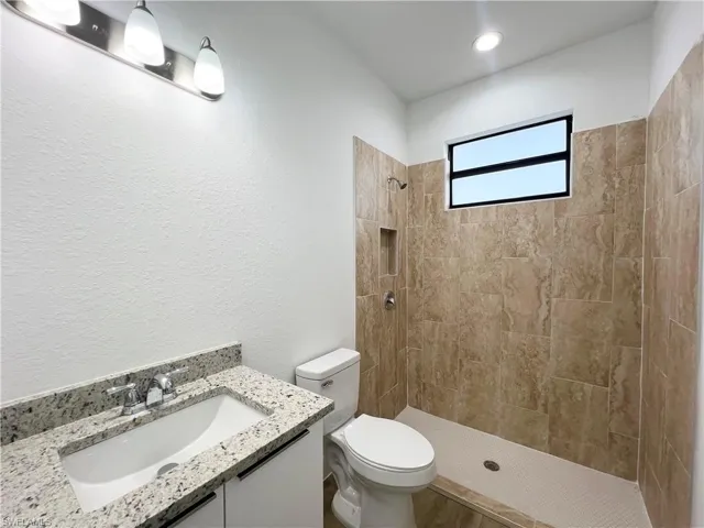 Bathroom with vanity, toilet, and tiled shower