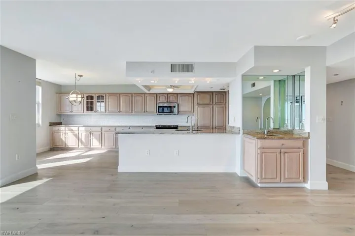 Kitchen featuring granite countertops, pendant lighting, decorative backsplash, and light wood flooring