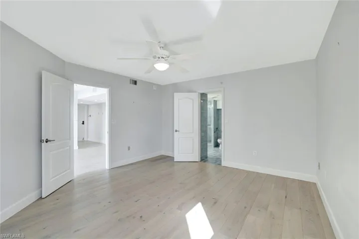 Primary bedroom with light wood flooring