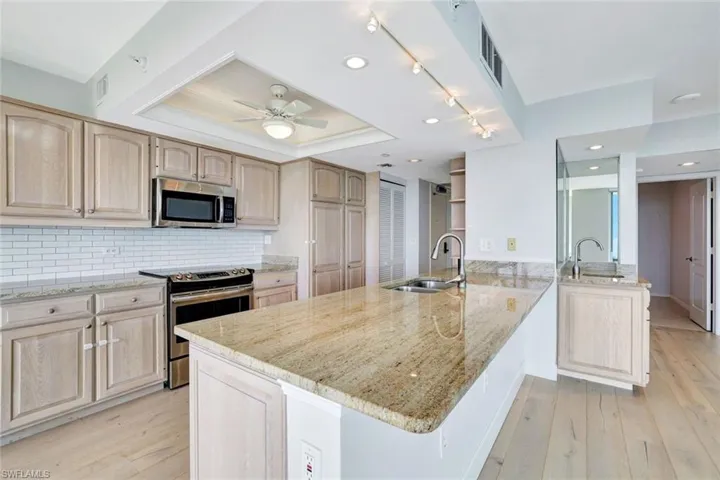 Kitchen with stainless steel appliances, light wood flooring and granite countertops
