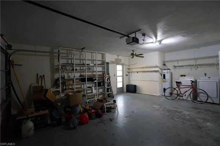 Garage with electric water heater, a garage door opener, washing machine and clothes dryer, and a ceiling fan