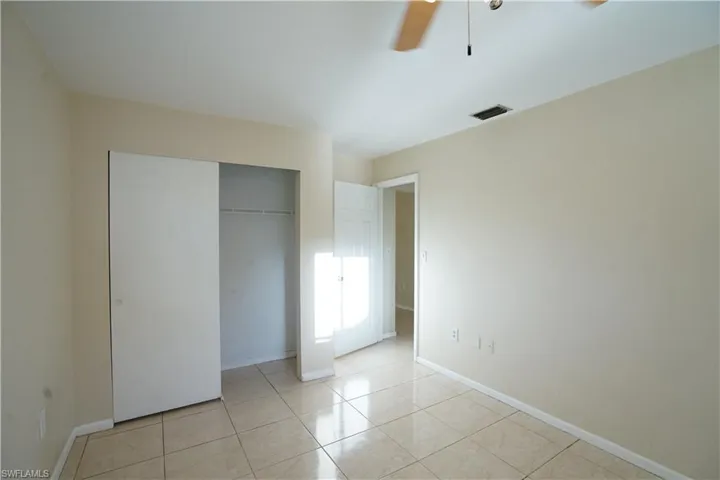 Unfurnished bedroom featuring light tile patterned floors, a ceiling fan, and a closet