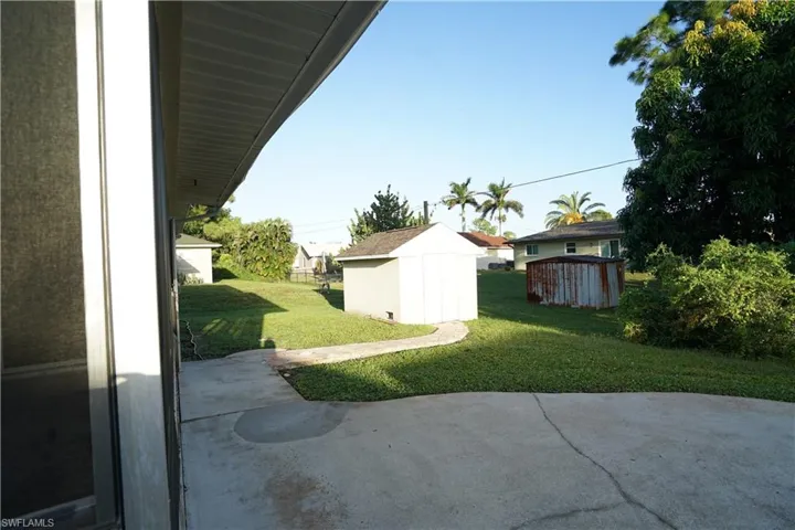 View of green lawn featuring a storage unit and a patio area