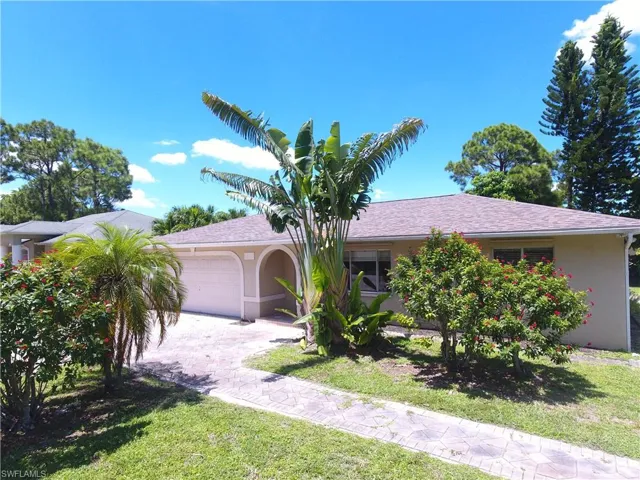 Ranch-style home featuring an attached garage, stucco siding, roof with shingles, and a front lawn