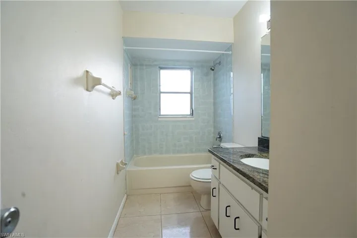 Bathroom featuring vanity, bathtub / shower combination, and light tile patterned flooring