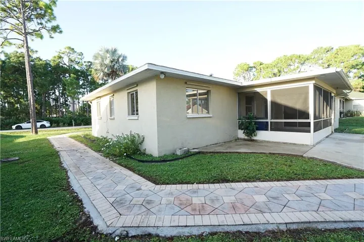 View of side of property with a sunroom, a yard, stucco siding, and a patio area