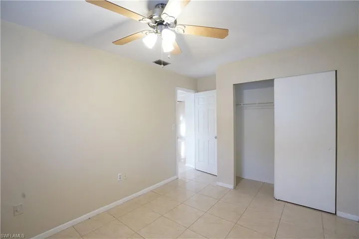 Unfurnished bedroom with light tile patterned floors, ceiling fan, and a closet