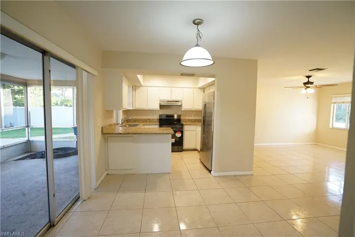 Kitchen featuring stainless steel appliances, white cabinets, pendant lighting, a peninsula, and light tile patterned floors