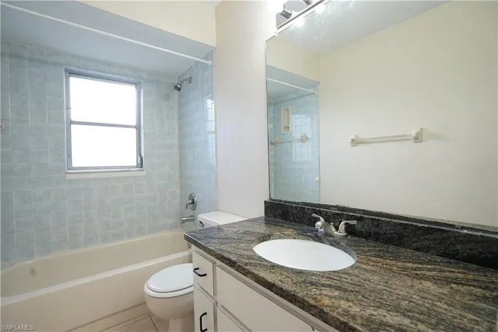 Bathroom with tub / shower combination, vanity, and light tile patterned floors