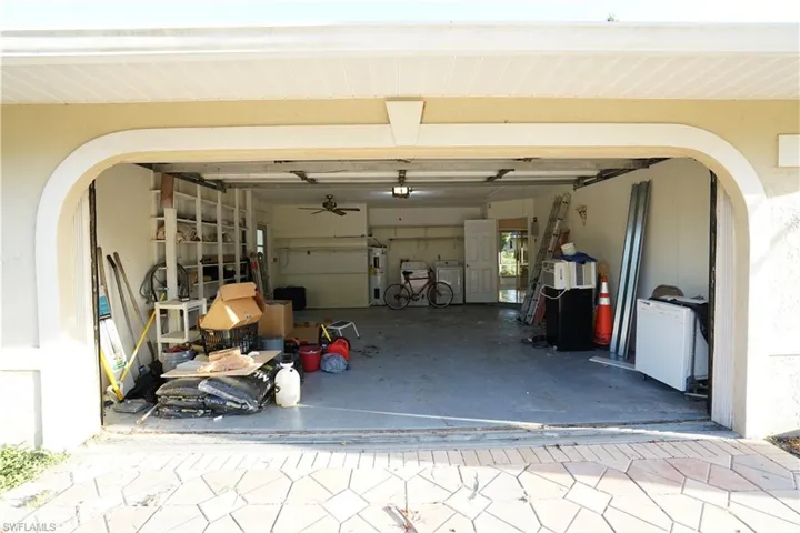 Garage with water heater, washing machine and dryer, and white fridge