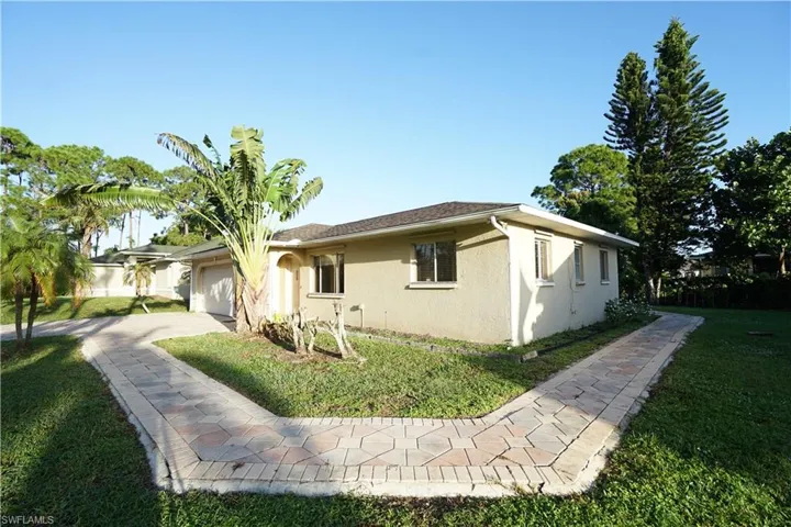 View of side of property with a yard, stucco siding, decorative driveway, and an attached garage