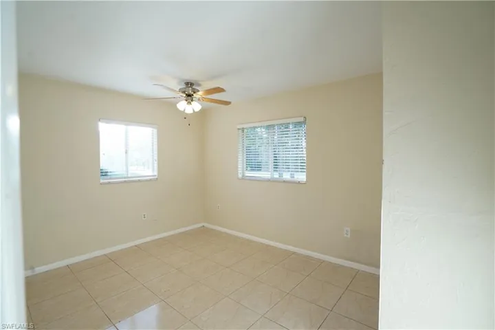 Empty room featuring light tile patterned floors, healthy amount of natural light, and ceiling fan