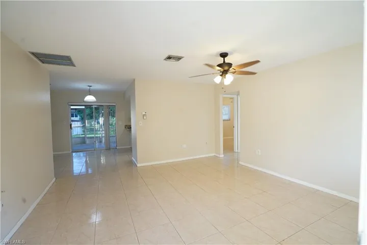 Empty room with light tile patterned floors and a ceiling fan