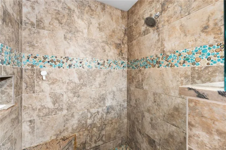 A stunning walk-in shower, beautifully accented with a decorative listello tile detail, adds a refined and elegant touch.