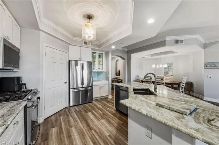 The reimagined chef’s kitchen is equipped with natural gas and features a spacious island adorned with exquisite granite, stainless steel appliances, a custom backsplash, and a tray ceiling enhanced by recessed lighting.