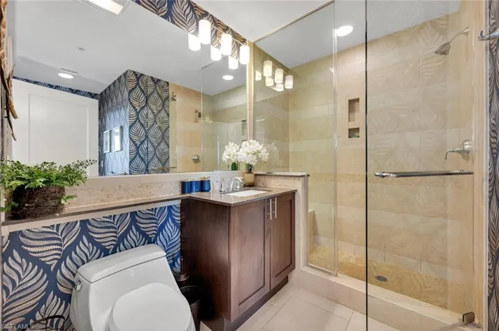 Bathroom with tile patterned floors, vanity, toilet, and a shower with shower door
