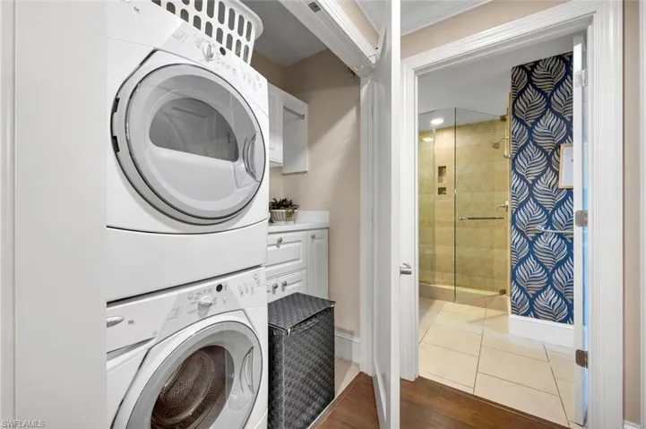 Laundry room with tile patterned flooring, stacked washer / drying machine, and crown molding