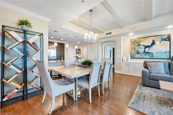 Dining area with wood-style flooring, ornamental molding, and a notable chandelier