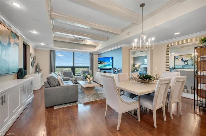 Dining space with beamed ceiling, hardwood style flooring, ornamental molding, and a chandelier