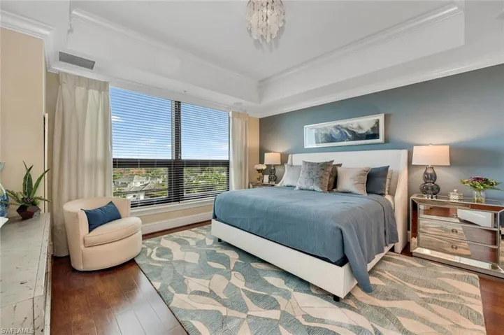 Bedroom featuring hardwood / wood-style flooring, crown molding, and a tray ceiling