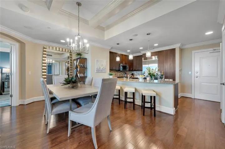 Dining space featuring beamed ceiling, dark hardwood / wood-style flooring, ornamental molding, and a chandelier