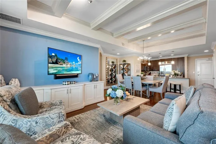 Living room featuring hardwood-style flooring, crown molding, and an inviting chandelier