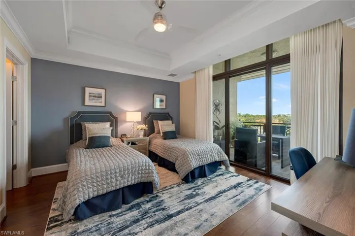 Bedroom featuring access to exterior, dark hardwood / wood-style flooring, a raised ceiling, and ceiling fan