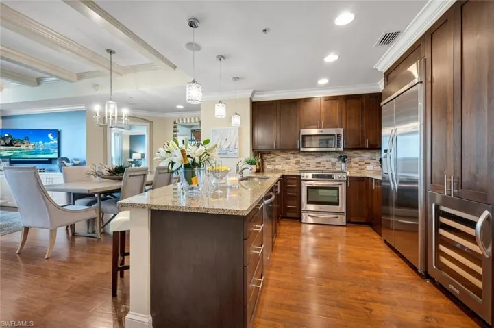 Kitchen featuring sink, light stone counters, water filter, backsplash, decorative light fixtures,  S/S appliances and Wine Bar
