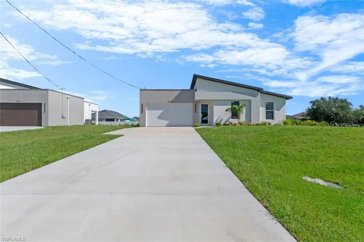 Contemporary house with a front lawn, stucco siding, a garage, and concrete driveway