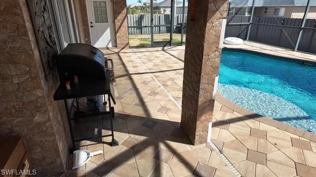 View of swimming pool featuring patio surround, a grill, and a lanai