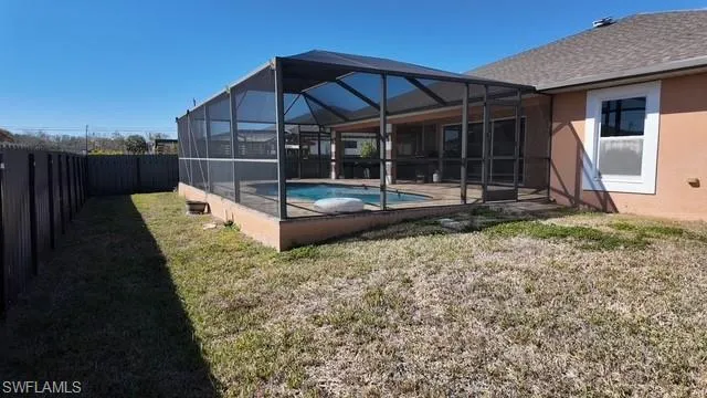 Rear view of house with a sunroom, a lanai, a fenced backyard, and stucco siding