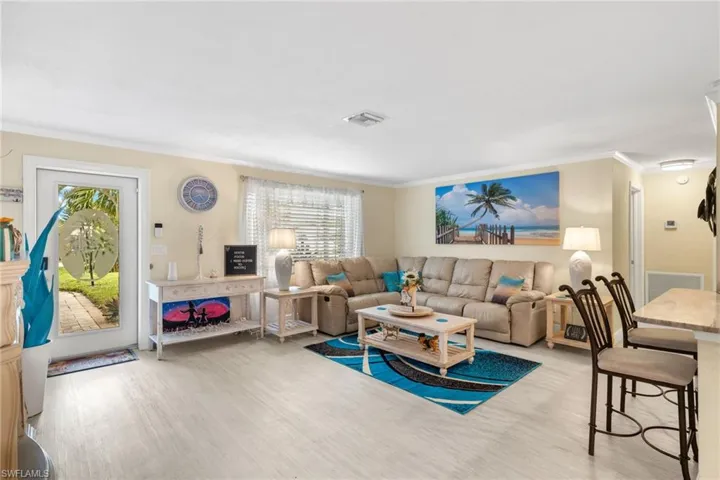 Living room featuring light hardwood / wood-style flooring, a healthy amount of sunlight, and crown molding