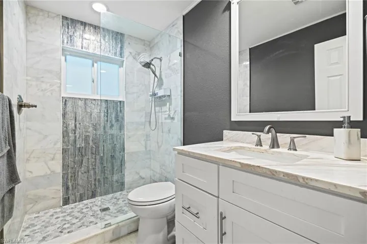 Bathroom with toilet, vanity, and a tile shower
