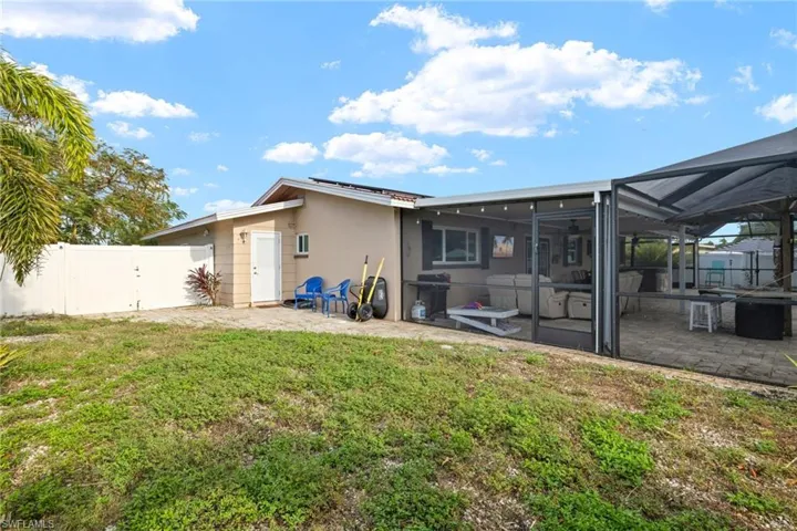 Rear view of property with a patio area, glass enclosure, and a lawn