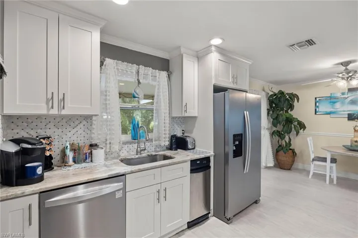 Kitchen with crown molding, sink, white cabinets, and stainless steel appliances