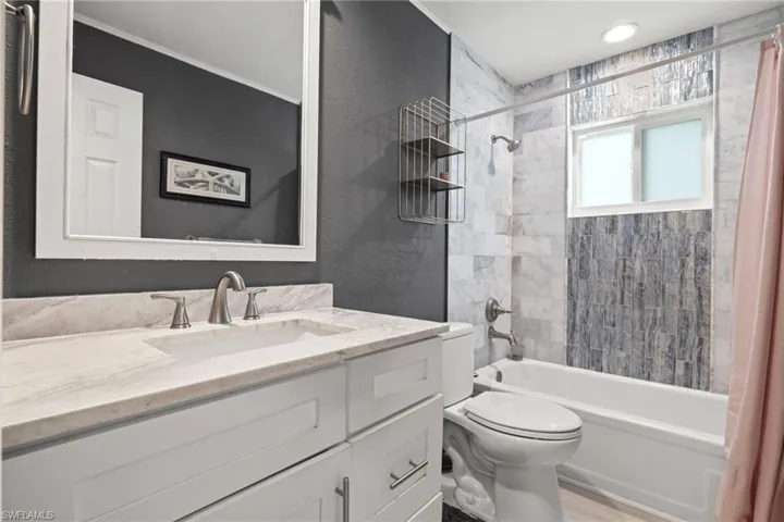 Full bathroom with vanity, shower / bath combination with curtain, wood-type flooring, and toilet
