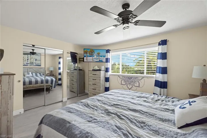 Bedroom with light hardwood / wood-style flooring, a textured ceiling, and ceiling fan