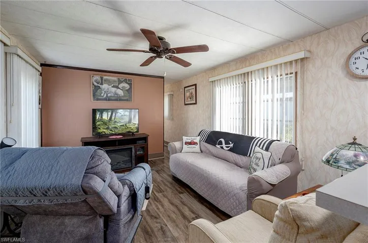 Living room with wood-type flooring, ceiling fan, and crown molding