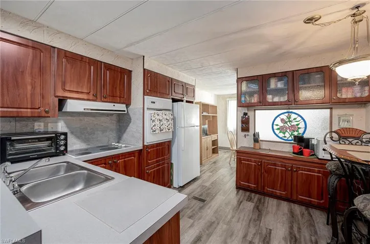 Kitchen with tasteful backsplash, pendant lighting, sink, light hardwood / wood-style floors, and white appliances