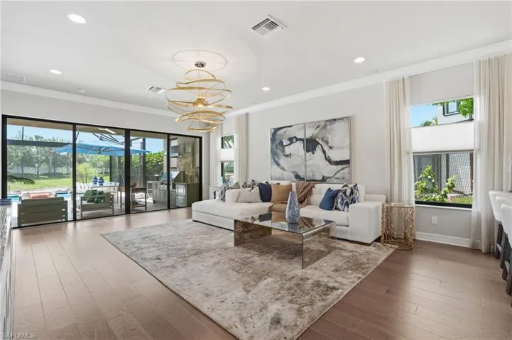 Open-concept living space with wood-finish flooring, recessed lighting, and a contemporary chandelier