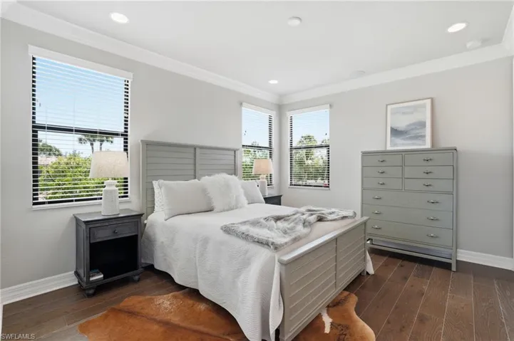 Bedroom featuring wood-finish flooring, recessed lighting, crown molding, and multiple windows